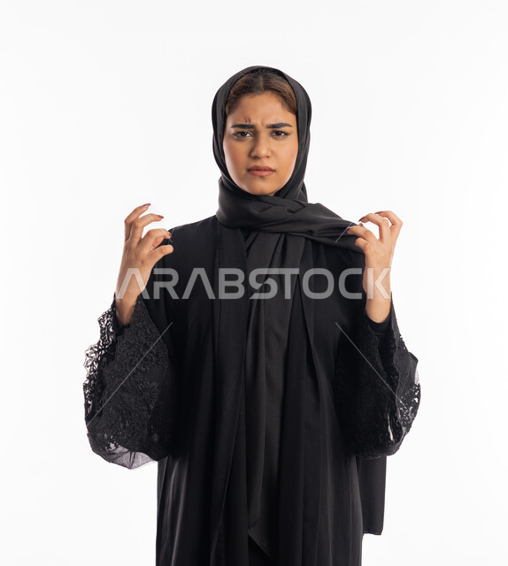 محاولة ضبط النفس وكتم الغضب, الحزن وطلب التوقف عن فعل الأخطاء, بورتريه لشابة عربية خليجية إماراتية ترتدي العباءة  السوداء ترفع يديها بانزعاج, سيدة سعودية تقف بإيماءات العتاب والتوبيخ والرفض, خلفية بيضاء