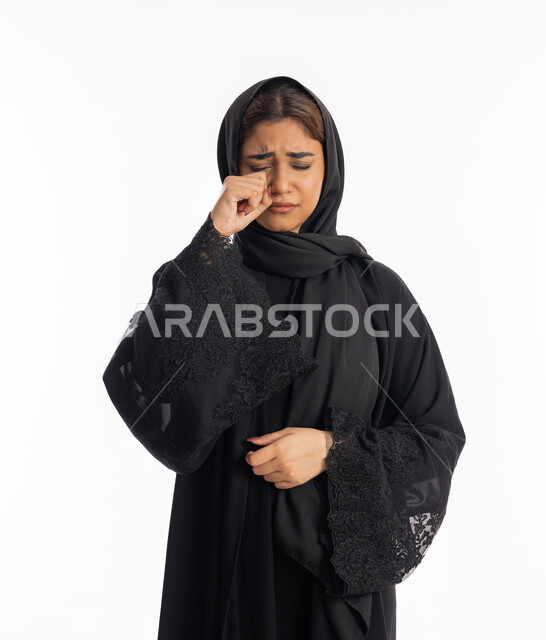فقدان وخسارة شيء ما, الوقوف بتعابير الخيبة واليأس, سماع خبر حزين, الشعور بالهم والاكتئاب, بورتريه مقرب لشابة عربية خليجية إماراتية ترتدي العباءة السوداء تضع يديها على عينيها بحزن, سيدة سعودية تقف بإيماءات البكاء والقهر, خلفية بيضاء