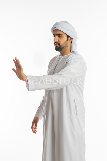 النهي عن فعل شيء ما, الصمت والتوقف عن الكلام, بورتريه لرجل عربي خليجي اماراتي يرتدي الكندورة والعمامة الاماراتية يرفع كفه للأعلى بإيماءات الرفض وعدم الرضى والقبول, طلب خفض الصوت والتهديد, خلفية بيضاء