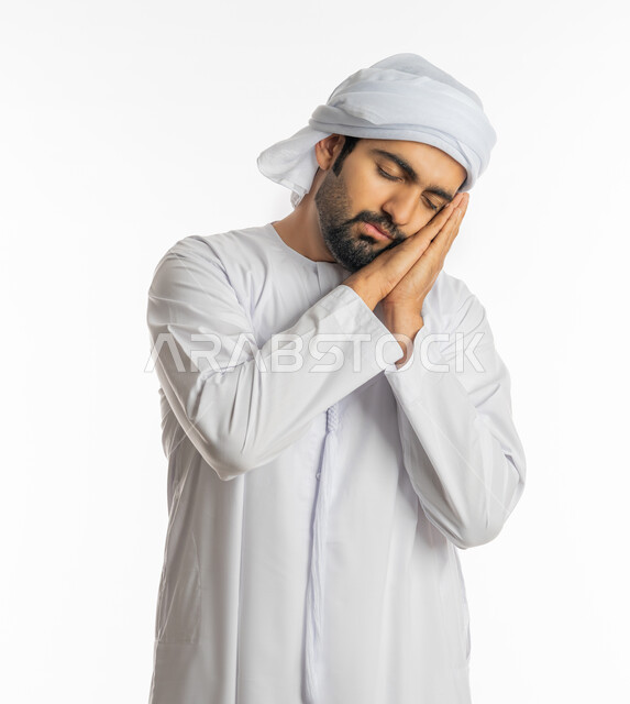مفهوم الحاجة إلى النوم والراحة والاسترخاء, الشعور بالتعب والنعاس والكسل, بورتريه لشاب عربي خليجي اماراتي يرتدي الكندورة والعمامة يغمض عينيه وينام بعمق, الإحساس بالخمول ودخول وقت النوم, خلفية بيضاء