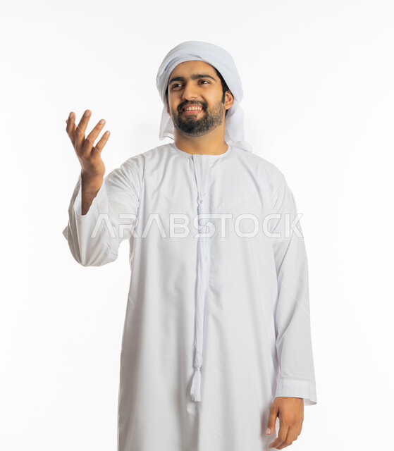 الإعجاب والسرور بشيء ما, بورتريه لشاب عربي خليجي إماراتي مبتسم يرتدي الكندورة والعمامة يرفع يديه بإيماءات المدح,  التفاعل والانسجام والترنم بسماع شيء ما, الفرح برؤية شخص معين, خلفية بيضاء