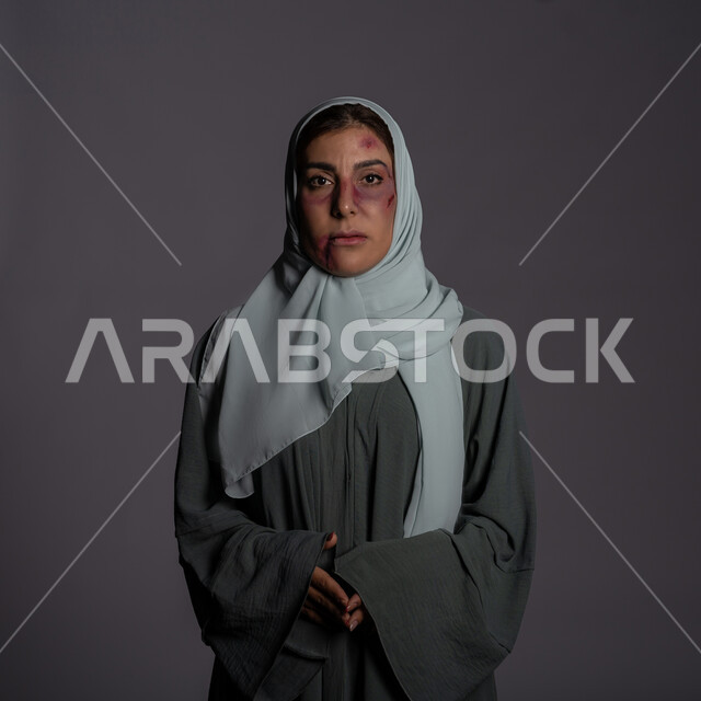 حقوق المرأة المسلمه, آثار الكدمات الجسدية, 25 نوفمبر اليوم العالمي للقضاء على العنف ضد النساء ,العلاقات الزوجية الفاشلة, بورتريه مقرب لشابة عربيه إماراتية خليجية محجبة تنظر الى الكاميرا بتعابير الصمت و التعب, سيدة سعودية حزينة, خلفية رمادية