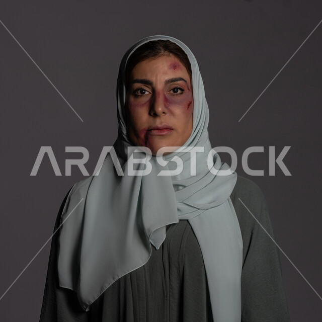 آثار الكدمات الجسدية, 25 نوفمبر اليوم العالمي للقضاء على العنف ضد النساء ,حقوق المرأة المسلمه, العلاقات الزوجية الفاشلة, بورتريه مقرب لشابة عربيه إماراتية خليجية محجبة تنظر الى الكاميرا بتعابير الصمت و التعب, سيدة سعودية حزينة, خلفية رمادية
