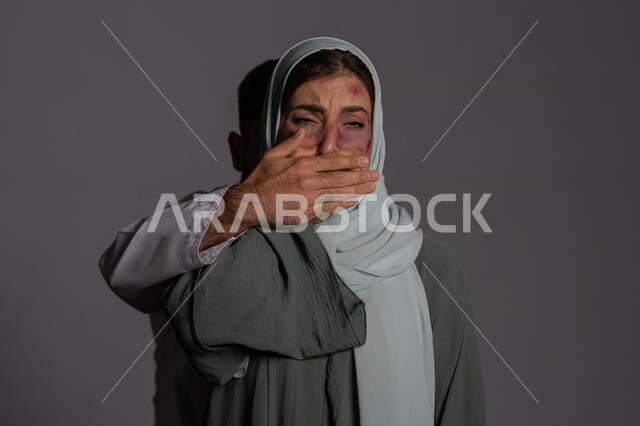 آثار الكدمات الجسدية ,إجبار الامرأة على السكوت من قبل الرجال ,حقوق المرأة المسلمه، اليوم العالمي للقضاء على العنف ضد النساء 25 نوفمبر ,العلاقات الزوجية الفاشلة, بورتريه مقرب لشابة عربيه إماراتية خليجية محجبة تنظر للكاميرا بتعابير البكاء, سيدة سعودية حزينة, خلفية رمادية
