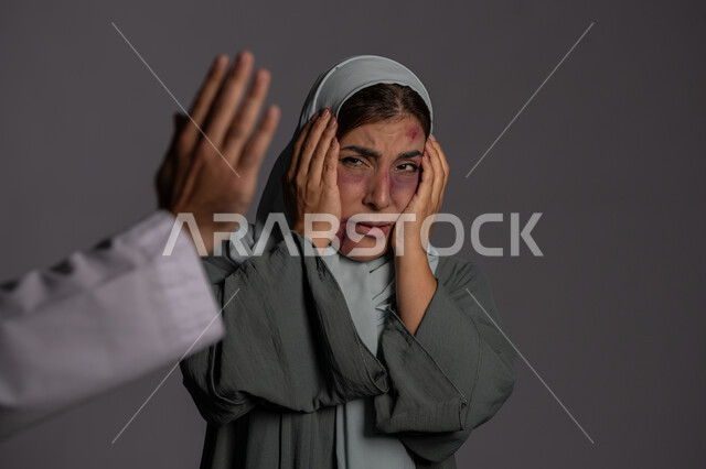 حقوق المرأة المسلمه ,آثار الكدمات البدنية, العلاقات الزوجية الفاشلة, 25 نوفمبر اليوم العالمي للقضاء على العنف ضد النساء ,التعرض للأذى الجسدي من قبل الرجال, بورتريه مقرب لشابة عربيه إماراتية خليجية محجبة تبتعد بتعابير الخوف و الذعر, سيدة سعودية حزينة, خلفية رمادية