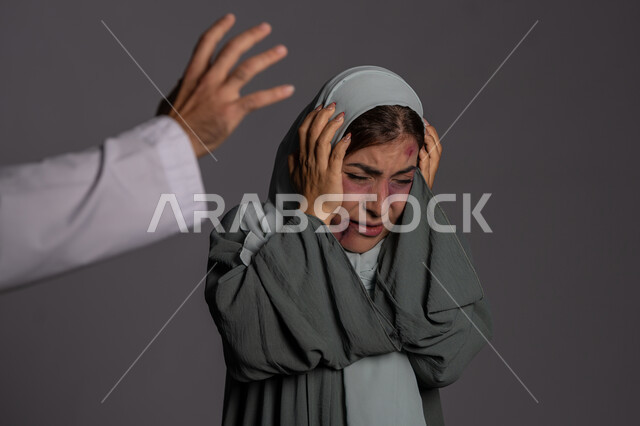 آثار الكدمات البدنية, العلاقات الزوجية الفاشلة, 25 نوفمبر اليوم العالمي للقضاء على العنف ضد النساء ,التعرض للأذى الجسدي من قبل الرجال, حقوق المرأة المسلمه ,بورتريه مقرب لشابة عربيه إماراتية خليجية محجبة تبتعد بتعابير الخوف و الذعر, سيدة سعودية حزينة, خلفية رمادية