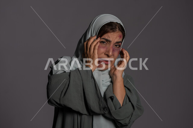 المشاكل الزوجية و الأمراض النفسية, 25 نوفمبر اليوم العالمي للقضاء على العنف ضد النساء ,حقوق المرأة المسلمه ,آثار الكدمات البدنية, بورتريه مقرب لشابة عربيه إماراتية خليجية محجبة ترفع يديها على وجهها بتعابير الخوف و حماية النفس, سيدة سعودية حزينة, خلفية رمادية