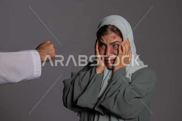 25 نوفمبر اليوم العالمي للقضاء على العنف ضد النساء، التعرض للأذى الجسدي من قبل الرجال, العلاقات الزوجية الفاشلة, سيدة سعودية حزينة, بورتريه مقرب لشابة عربيه إماراتية خليجية محجبة تضع يدها على وجهها بتعابير الخوف و البكاء, حقوق المرأة المسلمه، خلفية رمادية