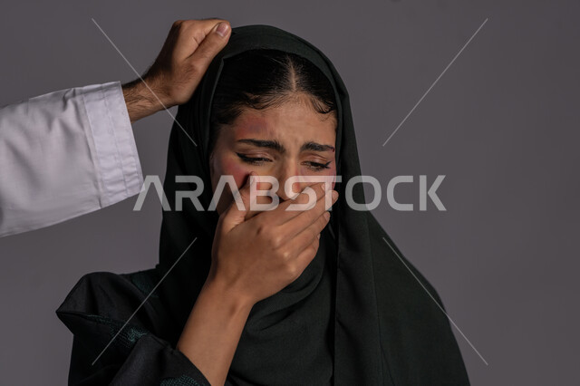سيدة سعودية حزينة, التعرض للأذى الجسدي من قبل الرجال, العلاقات الزوجية الفاشلة, 25 نوفمبر اليوم العالمي للقضاء على العنف ضد النساء ,بورتريه مقرب لشابة عربيه إماراتية خليجية محجبة تضع يدها على فمها بتعابير البكاء, حقوق المرأة المسلمه، خلفية رمادية