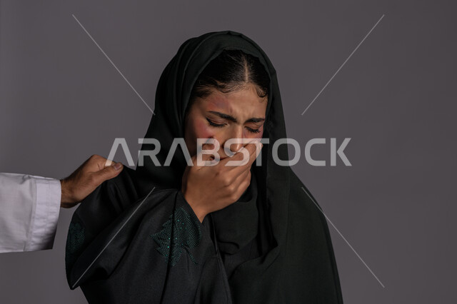 Exposure to physical harm by men, failed marital relationships, November 25 International Day for the Elimination of Violence against Women, close-up portrait of a veiled Arab Emirati Gulf young woman, putting her hand over her mouth with a crying expression, a sad Saudi woman, Muslim women’s rights, gray background