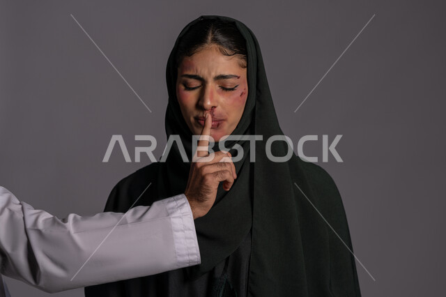Muslim women’s rights, hiding traces of physical bruises, International Day for the Elimination of Violence against Women, November 25, women being forced to remain silent by men, failed marital relations, close-up portrait of a veiled Emirati Gulf Arab young woman closing her eyes with an expression of collapse, a sad Saudi woman, gray background