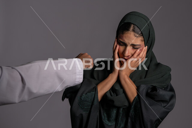 25 نوفمبر اليوم العالمي للقضاء على العنف ضد النساء ,حقوق المرأة المسلمه ,يد رجل مقبوضة بتعابير الضرب ,علاقات اسرية فاشلة, آثار الكدمات البدنية, بورتريه مقرب لشابة عربيه إماراتية خليجية محجبة تتعرض للأذى الجسدي من قبل الرجال ,سيدة سعودية حزينة, خلفية رمادية