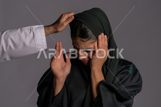 العلاقات الاسرية الفاشلة, التعرض للأذى الجسدي من قبل الرجال, الدفاع عن حقوق المرأة المسلمه ,25 نوفمبر اليوم العالمي للقضاء على العنف ضد النساء ,آثار الكدمات البدنية, بورتريه مقرب لشابة عربيه إماراتية خليجية محجبة ترفع يديها بتعابيرالخوف, سيدة سعودية حزينة, خلفية رمادية
