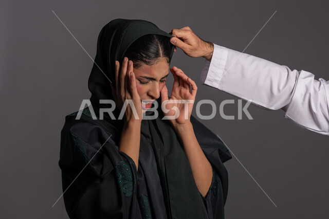 التعرض للأذى الجسدي من قبل الرجال, الدفاع عن حقوق المرأة المسلمه ,العلاقات العائلية الفاشلة, 25 نوفمبر اليوم العالمي للقضاء على العنف ضد النساء ,آثار الكدمات البدنية, بورتريه مقرب لشابة عربيه إماراتية خليجية محجبة ترفع يديها بتعابيرالخوف, سيدة سعودية حزينة, خلفية رمادية