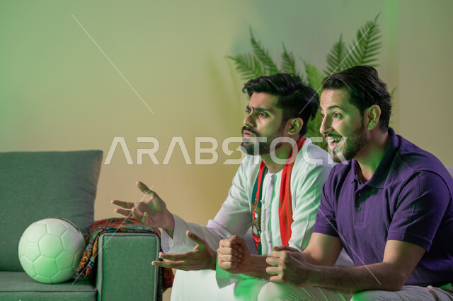 قضاء وقت ممتع في البيت مع الاصدقاء , صديقان عربيان اماراتيان خليجيان يشاهدان مباراة للدوري العربي  في المنزل, ايماءات الحماس والتحدي , أندية وتشجيع
