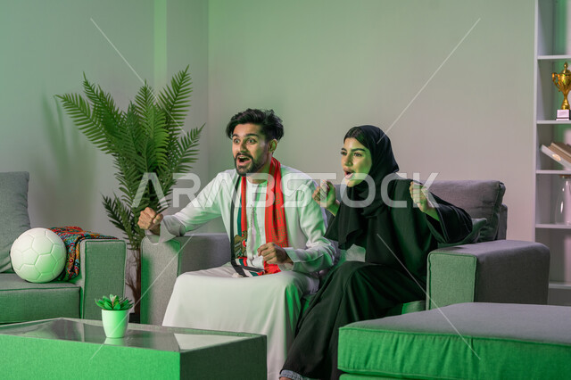 اوشحة تشجيعية باللون الاحمر لكرة القدم, ايماءات الحماس والفرحة بالفوز, زوجان عربيان اماراتيان خليجيان يشاهدان مباراة للدوري العربي يشجعان فريق الامارات, أندية وتشجيع .