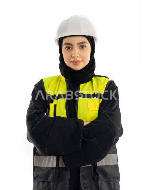 الإشراف على المشاريع ومتابعة سيرها، مفهوم الهندسه المعماريه, بورتريه مقرب لمهندسة عربية خليجية اماراتية ترتدي العباية وسترة وخوذة الحماية تقف بأيدي مكتوفة, فتاة سعودية محجبة تنظر إلى الكاميرا بإيماءات الحزم والجدية, مهن ووظائف هندسيه، خلفية بيضاء