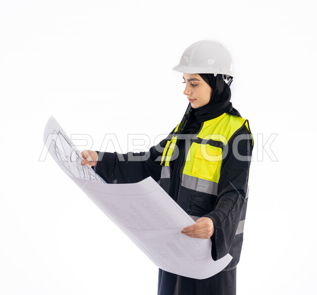 الإشراف على المشاريع الإنشائية، متابعة وتدقيق المخططات, بورتريه من الجانب لمهندسة عربية خليجية اماراتية ترتدي العباية وسترة وخوذة الحماية تحمل بيدها مخطط البناء, فتاة سعودية محجبة تنظر إلى رسومات المشروع, مهن ووظائف هندسيه، مفهوم الهندسه المعماريه, خلفية بيضاء
