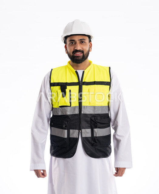 مهن ووظائف هندسية، الوقوف باستقامة والنظر إلى الكاميرا بإيماءات البهجة والسرور, الاهتمام بالتطور العمراني بسواعد المهندسين الإماراتيين، بورتريه لمهندس عربي خليجي إماراتي مبتسم يرتدي سترة العمل وخوذة الحماية، خلفية بيضاء