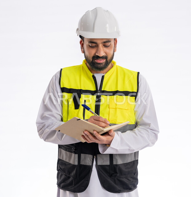 إيماءات البهجة والسرور، تدوين وتسجيل الملاحظات، الإشراف على الأعمال ومتابعة سيرها، مهن ووظائف هندسية، الاهتمام بالتطور العمراني بسواعد المهندسين في الإمارات العربية المتحدة بورتريه لمهندس عربي خليجي إماراتي مبتسم يرتدي سترة العمل وخوذة الحماية، خلفية بيضاء