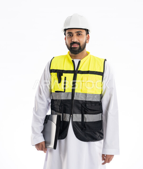 Following up and supervising the progress of work, looking at the camera with gestures of joy and pleasure, engineering professions and jobs, interest in urban development by the hands of engineers in the United Arab Emirates, portrait of an Arab Gulf Emirati engineer wearing a work jacket and a protective helmet holding construction records, white background