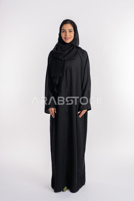 Young Saudi woman taking a selfie for official documents, modern veiled fashion, concept of elegance and interest in appearance, portrait of a veiled Arab Gulf Emirati woman wearing a modern abaya and looking at the camera with gestures of pleasure and self-confidence, full body photo, white background