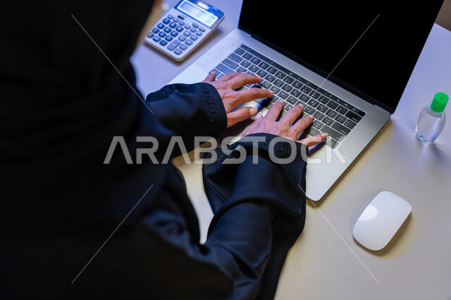 استخدام الاجهزة التقنية الحديثة، مهن ووظائف نسائية، الاهتمام بالنظافة واتباع الاجراءات الوقائية من فايروس كورونا، صورة مقربة لإمرأة عربية خليجية إماراتية تقوم بالكتابة على الحاسوب المحمول, شابة سعودية تضع علبة المواد الكيميائية والكحول امامها للقضاء على الفايروسات