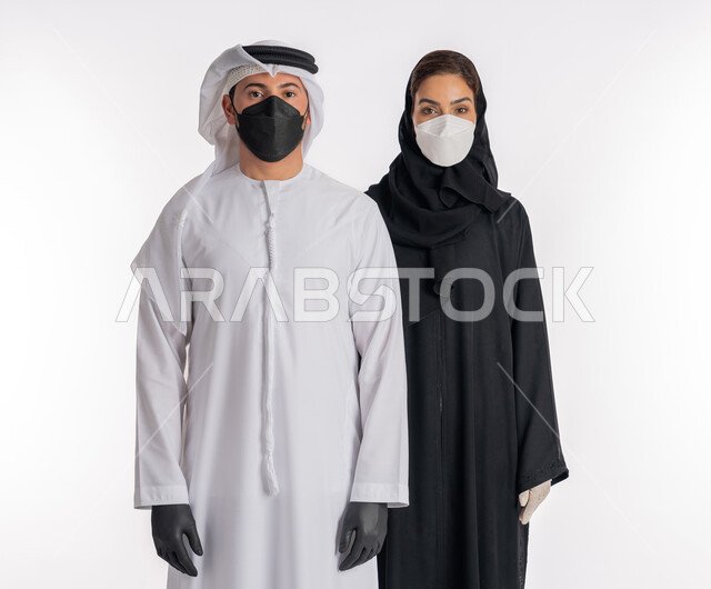 اتباع إجراءات السلامة للوقاية من العدوى, توخي الحذر من انتشار فيروس كورونا, بورتريه مقرب لزوجين عربيين خليجيين إماراتيين يرتديان القفازات والكمامة للحيطة من انتقال المرض, منع وتجنب ملامسة الايدي للجراثيم,  خلفية بيضاء