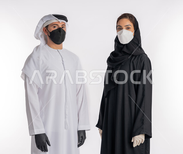 اتباع إجراءات السلامة للوقاية من العدوى, توخي الحذر من انتشار فيروس كورونا, بورتريه مقرب لزوجين عربيين خليجيين إماراتيين يرتديان القفازات والكمامة للحيطة من انتقال المرض, منع وتجنب ملامسة الايدي للجراثيم,  خلفية بيضاء