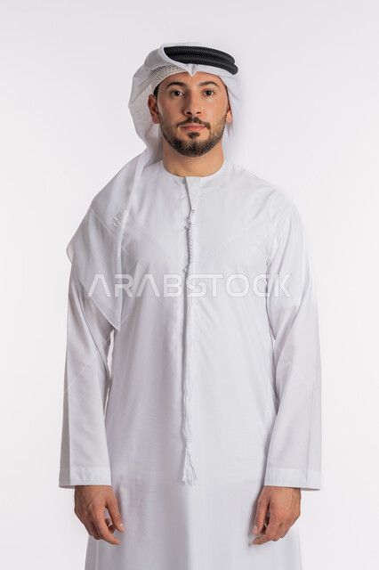 الأناقة والاهتمام بالمظهر الخارجي، التقاط الصور الشخصية للوثائق الرسمية، مفهوم الرجولة والثقة بالنفس، بورتريه مقرب لرجل عربي خليجي إماراتي يرتدي الكندورة والغترة ينظر الى الكاميرا بتعابير الحزم والجدية، الوقوف باستعداد واستقامة، خلفية بيضاء