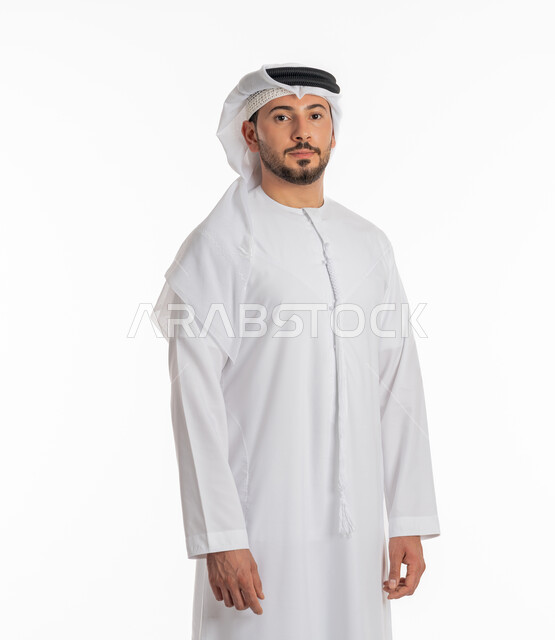 Taking portraits for official documents, concept of masculinity and self-confidence, close-up portrait of an Arab Gulf Emirati man wearing a kandura and ghutra looking at the camera with an expression of firmness and seriousness, standing ready and straight, elegance and interest in outward appearance, white background