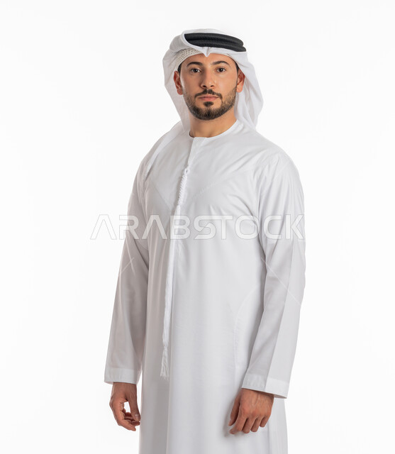 الوقوف باستعداد واستقامة، الأناقة والاهتمام بالمظهر الخارجي، التقاط الصور الشخصية للوثائق الرسمية، مفهوم الرجولة والثقة بالنفس، بورتريه مقرب لرجل عربي خليجي إماراتي يرتدي الكندورة والغترة ينظر الى الكاميرا بتعابير الحزم والجدية، خلفية بيضاء