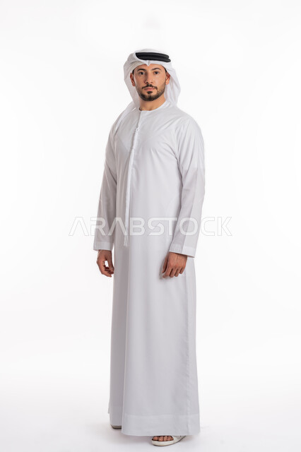 التقاط الصور الشخصية للوثائق الرسمية، مفهوم الرجولة والثقة بالنفس، بورتريه لرجل عربي خليجي إماراتي يرتدي الكندورة والغترة ينظر الى الكاميرا بتعابير الحزم والجدية، الوقوف باستعداد واستقامة، الأناقة والاهتمام بالمظهر الخارجي، صورة الجسم بالكامل، خلفية بيضاء