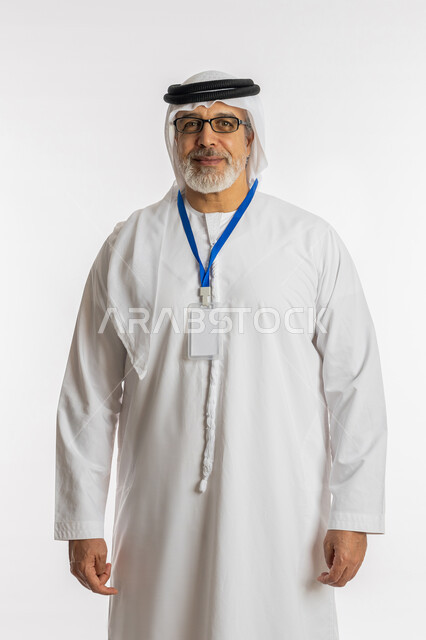 توضيح أهمية الهوية الشخصية، الوقوف باستقامة والنظر إلى الكاميرا، موك اب ابيض، كرت فارغ مستطيل الشكل, بورتريه لرجل مسن عربي اماراتي خليجي مبتسم يرتدي الغترة و الكندورة و النظارات الطبية يضع على رقبته بادج شخصي, خلفية بيضاء