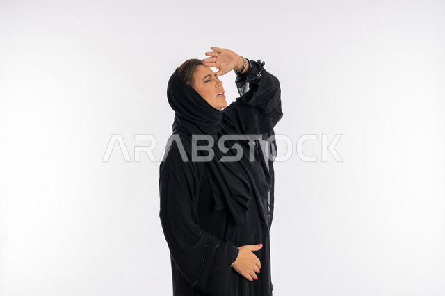 الحماية من الاذى وأشعة الشمس، بورتريه لامرأة عربيه سعودية محجبة ترتدي العباءه السوداء ترفع يدها للاعلى بتعابير محاولة رؤية شيء ما, سيدة خليجية اماراتية تقوم بإلقاء التحية و السلام, خلفية بيضاء