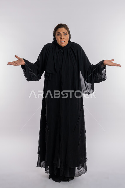الصدمة و الاستغراب و الدهشة عند سماع خبر ما، سيدة سعودية عربية تفتح يديها بتعابير الإستفهام حول موضوع معين, الغموض وعدم الوضوح، بورتريه لامرأة خليجية اماراتية محجبة ترتدي العباءة السوداء تفتح ذراعيها بإيماءات عدم المعرفة، الجسم بالطول الكامل, خلفية بيضاء