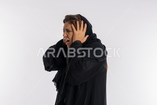 الامراض النفسيه و الحياه الفاشله ,تعابير الصراخ الشديد و العصبية ,بورتريه مقرب لامرأة عربيه خليجية اماراتية محجبة ترتدي العباءة السوداء تضع يديها على رأسها بإيماءات الغضب, سيدة سعودية تشعر بالندم على فعل شي ما, الوقوع في مصيبة, خلفية بيضاء