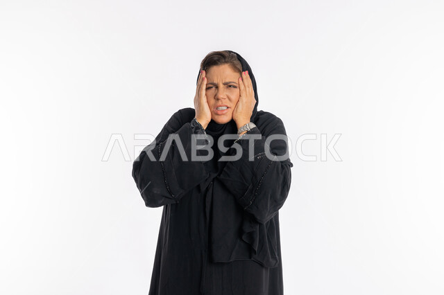 الوقوع في مصيبه, تعابير الدهشه و الانزعاج ,بورتريه مقرب لإمرأة عربيه سعوديه محجبة ترتدي العباءه السوداء تضع يديها على رأسها بايماءات الندم على شيء ما و الشعور بالاحباط, سيدة اماراتية خليجية تشعر بالخسارة و الحزن, خلفية بيضاء