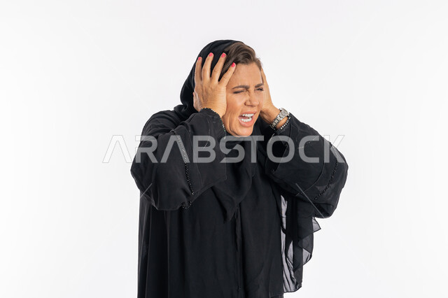 الوقوع في مصيبه, الندم على شيء ما و الشعور بالاحباط, بورتريه مقرب لإمرأة عربيه سعوديه محجبة ترتدي العباءه السوداء تضع يديها على رأسها بتعابير الدهشه و الانزعاج, سيدة اماراتية خليجية تشعر بالخسارة و الحزن, خلفية بيضاء
