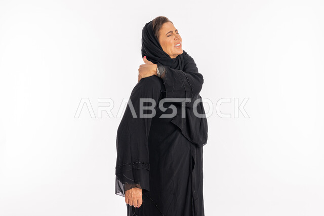 الشعور بالتعب و المرض, الحاجه للعلاج وطلب المساعده، بورتريه لامرأة خليجيه إماراتية ترتدي العباءة السوداء تعاني من التهاب العضلات والمفاصل، سيدة عربية سعودية تضع يدها على كتفها بإيماءات تدل على الألم الشديد، خلفية بيضاء