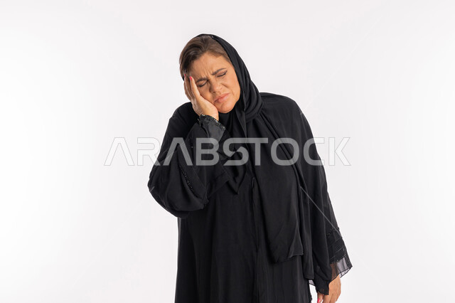 الإرهاق و التعب و الحاجه للعلاج, طلب المساعده للذهاب الى المستشفى، بورتريه مقرب لسيدة عربية سعودية محجبة ترتدي العباءة السوداء تضع يدها على رأسها بتعابير الدوخة وعدم التوازن, امرأة خليجية اماراتية تشعر بالمرض و الصداع, خلفية بيضاء