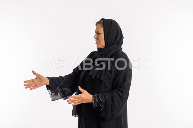 فتح الذراعين بايماءات النفور ,بورتريه مقرب لسيدة عربيه سعودية محجبة ترتدي العباءة السوداء تنظر الى شيء ما بتعابير الاشمئزاز, امرأة اماراتية خليجية ترفع يديها بحركات تدل على القرف, خلفية بيضاء