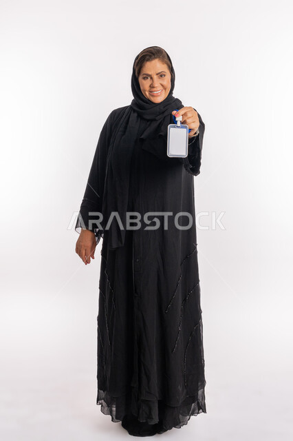 White mockup, blank rectangular card display, portrait of a smiling Saudi Arab woman wearing a black abaya, holding an identification card in her hand, an Emirati Gulf woman looking at the camera with gestures of happiness and pleasure, explaining the importance of personal identity, full-length body, white background.
