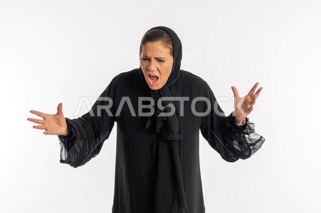 الامراض النفسيه و الحياه الفاشله ،بورتريه مقرب لامرأة عربيه خليجية اماراتية محجبة ترتدي العباءة السوداء ترفع يديها للأعلى بايماءات الغضب و العصبية و الاثارة, تعابير الصراخ الشديد, سيدة سعودية تشعر بالانزعاج و الرغبة بالانتقام, خلفية بيضاء