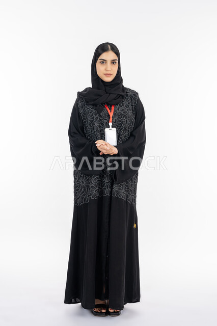 التعبير عن الذات, ايماءات الثقة بالنفس, بورتريه لإمرأة عربية خليجية إماراتية ترتدي العباءة تنظر إلى الكاميرا, سيدة سعودية تضع بطاقة فارغة بشريط أحمر, ارتداء بادج شخصي,  مفهوم الأناقة والاهتمام بالمظهر الخارجي, صورة الجسم بالطول الكامل, خلفية بيضاء