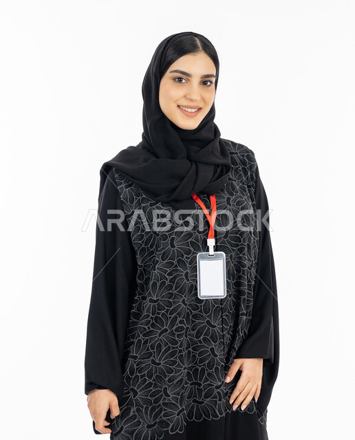 Identification card for students and employees, looking at the camera with an expression of pleasure, a portrait of a Gulf Arab Emirati young woman wearing an abaya and wearing a personal badge with a red ribbon, a Saudi woman standing with a smile, personal identity and self-expression, white background