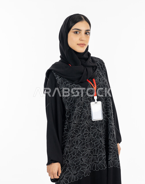 بطاقة تعريفية للطلاب والموظفين, الوقوف باستقامة بإيماءات الجدية والثقة بالنفس, بورتريه لإمرأة عربية خليجية إماراتية ترتدي العباءة تضع بادج شخصي بشريط أحمر, سيدة سعودية تنظر إلى الكاميرا, أناقة النساء الخليجيات, الاهتمام بالمظهر الخارجي, خلفية بيضاء