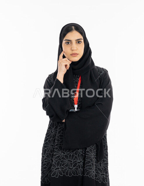 التفكير والحيرة وصعوبة اختيار شيء ما, ايجاد حل لمشكلة معينة, شرود الذهن والتخطيط لشيء معين, بورتريه لشابة عربية خليجية إماراتية ترتدي العباءة تنظر إلى الكاميرا, سيدة سعودية تضع يدها على وجهها, خلفية بيضاء