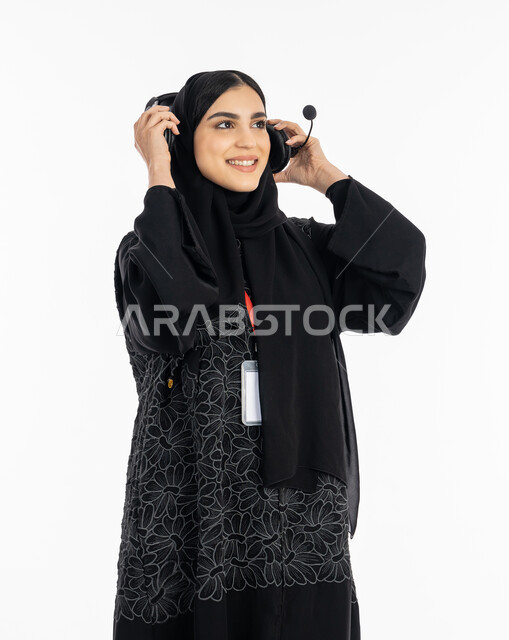 ارتداء بادج شخصي بشريط أحمر, تقديم البرامج الاذاعية، بورتريه لإمرأة عربية خليجية اماراتية ترتدي العباءة تضع سماعة الهيدفون، العمل في مجال خدمة العملاء، الاندماج والنظر إلى شيء ما بسرور, سيدة سعودية تقوم بالرد على استفسارات الزبائن ببشاشة، خلفية بيضاء