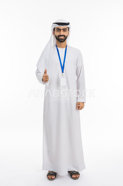 Personal identification card with the employee’s name, a blank rectangular white mock-up, raising a finger with gestures of quality and excellence, portrait of an Arab Gulf Emirati businessman wearing a kandora and ghutra looking at the camera with a smile, wearing a personal badge, full-length body portrait, white background